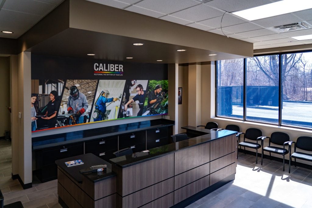 Modern electrical contractor office lobby with branded Caliber wall mural and reception desk