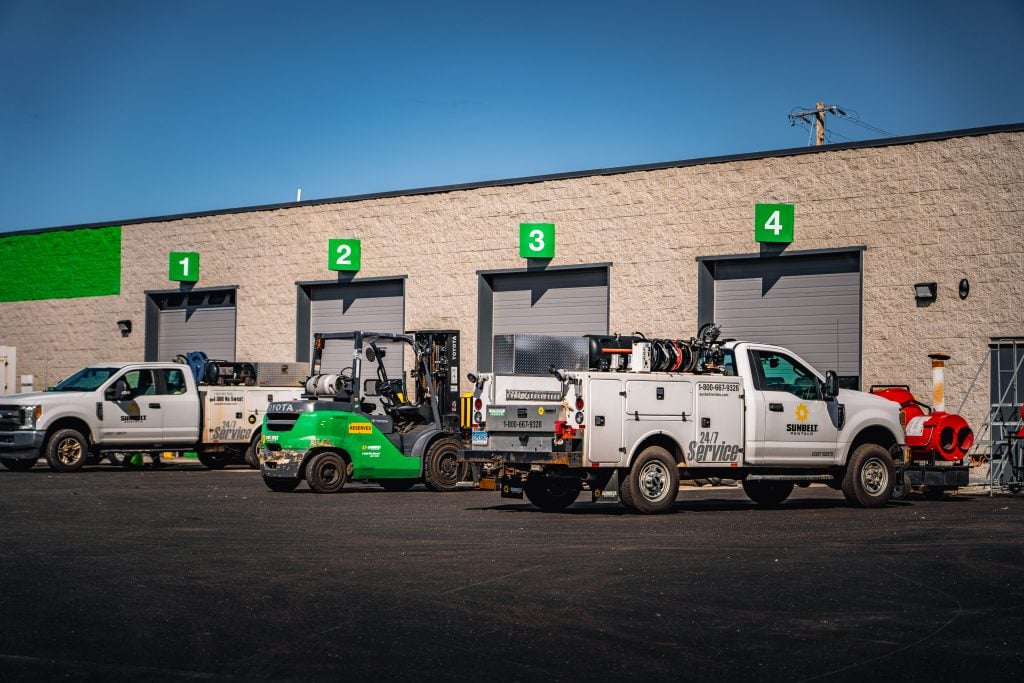 Lupo Electric service trucks and equipment staged outside industrial facility with four loading bays