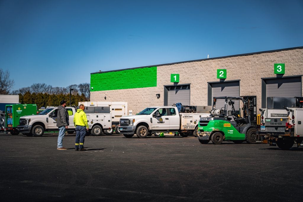 Lupo Electric service vehicles and crew outside commercial facility with labeled bays