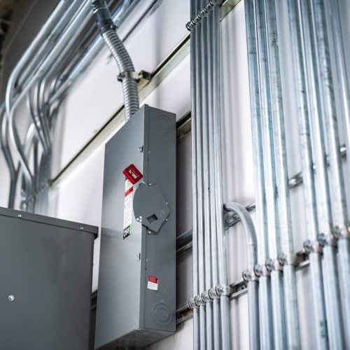 Commercial electrical disconnects and neatly routed conduit on white interior wall