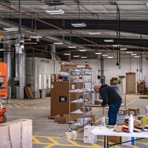Interior of commercial warehouse under construction with conduit, lighting, and workstations