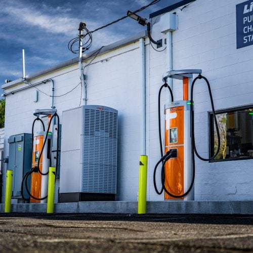 Commercial EV charging stations installed outside white building with bollard protection