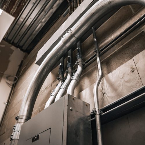 Overhead commercial conduit and electrical panel installation in progress