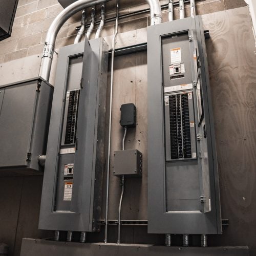 Dual commercial electrical panels with conduit and distribution wiring installed on interior wall