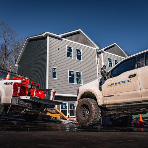 Lupo Electric service trucks parked at a residential construction site