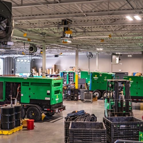 Interior of industrial facility with large green generators and overhead electrical systems